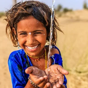 a littile girl in thar desert seems to be happy after seeing water